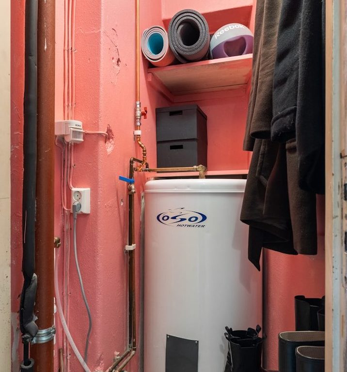 A bathroom with a hot water heater next to a closet