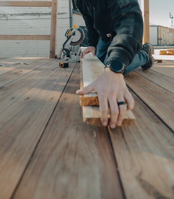 A person wearing safety glasses cuts wood with a saw.