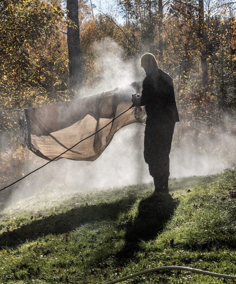 Man spraying water on a tarp outdoors